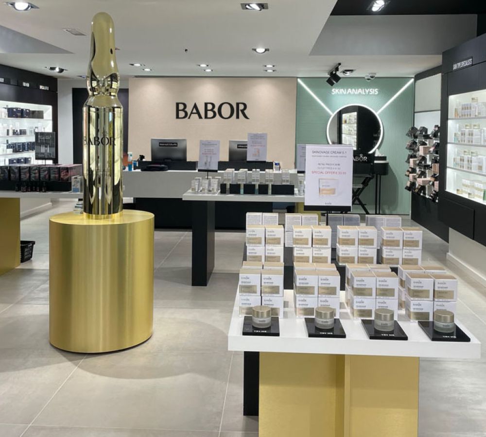 Verkaufsraum eines BABOR Stores mit hellem Großformat-Fliesenboden und goldener Ampullen-Skulptur