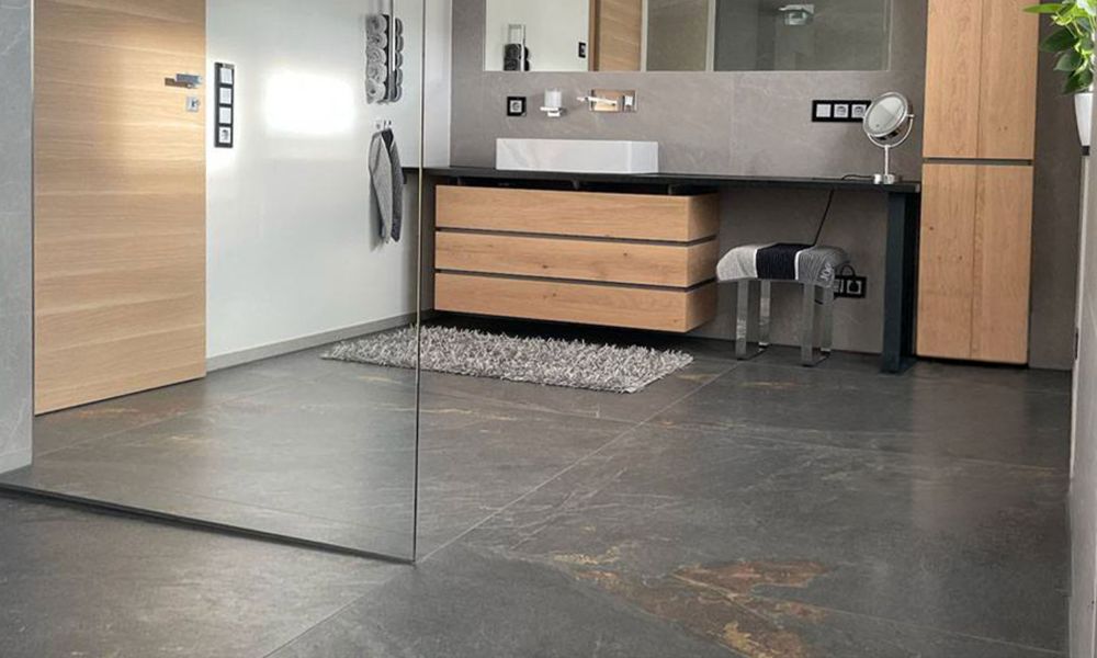 Barrierefreies Badezimmer mit bodengleicher Dusche und großformatigen Fliesen in Schieferoptik